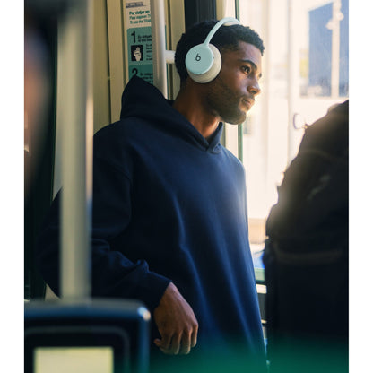 Man wearing light blue Beats 360 headphones on public transit for travel