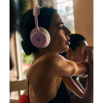 Woman wearing pink and cream Beats 360 headphones during workout for active lifestyle use at Nuvana Tech